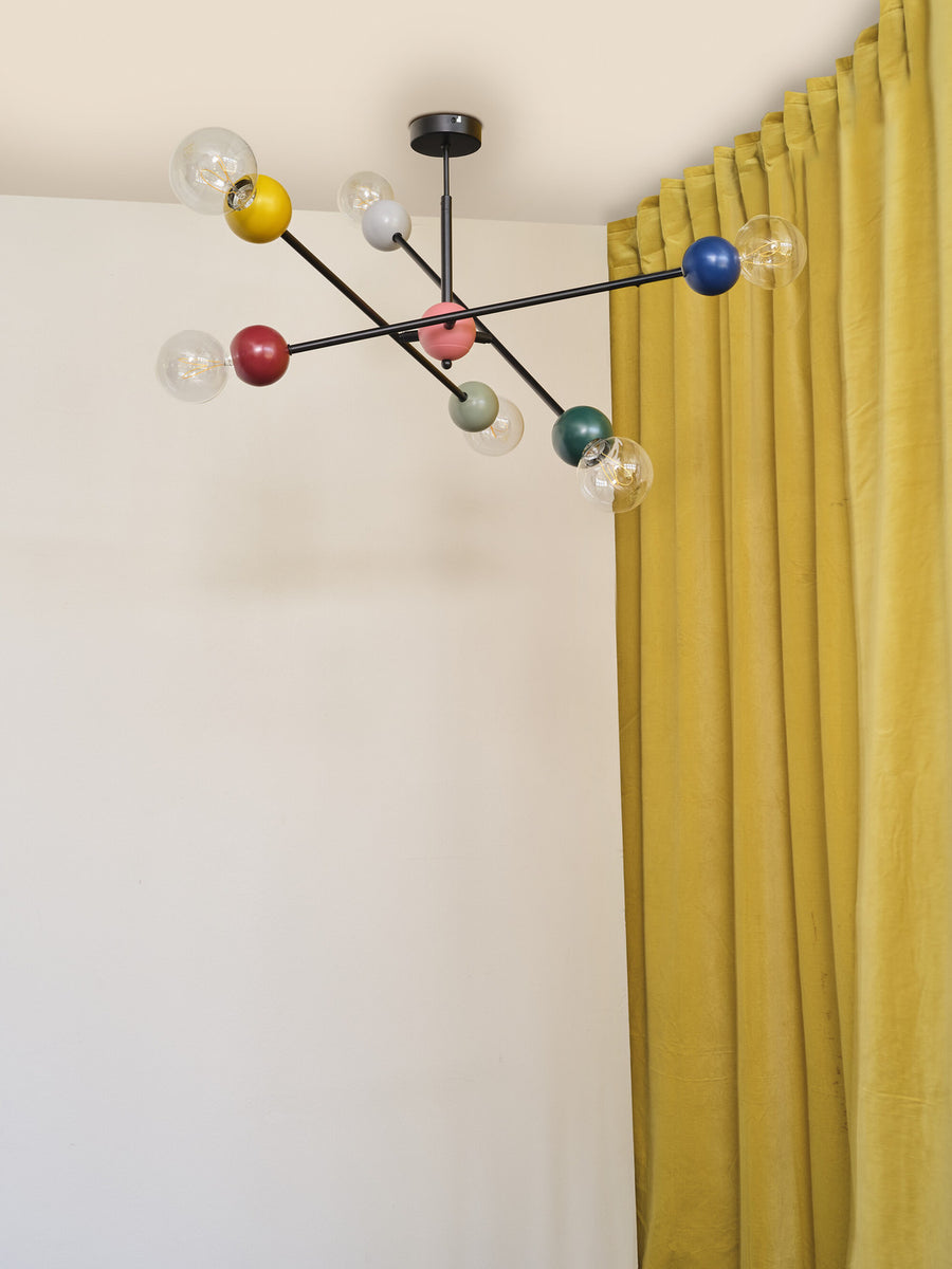 Vue rapprochée du luminaire allumé devant un rideau jaune et un mur blanc.