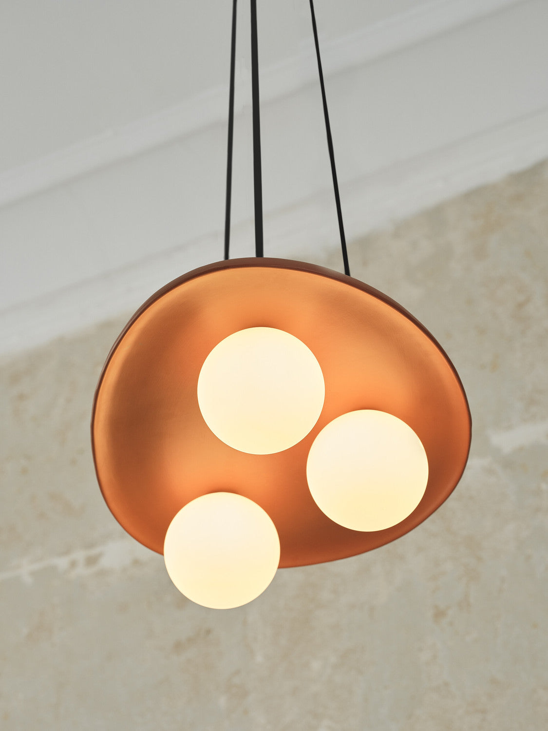 Détail rapproché du disque terracotta et des trois globes lumineux allumés.