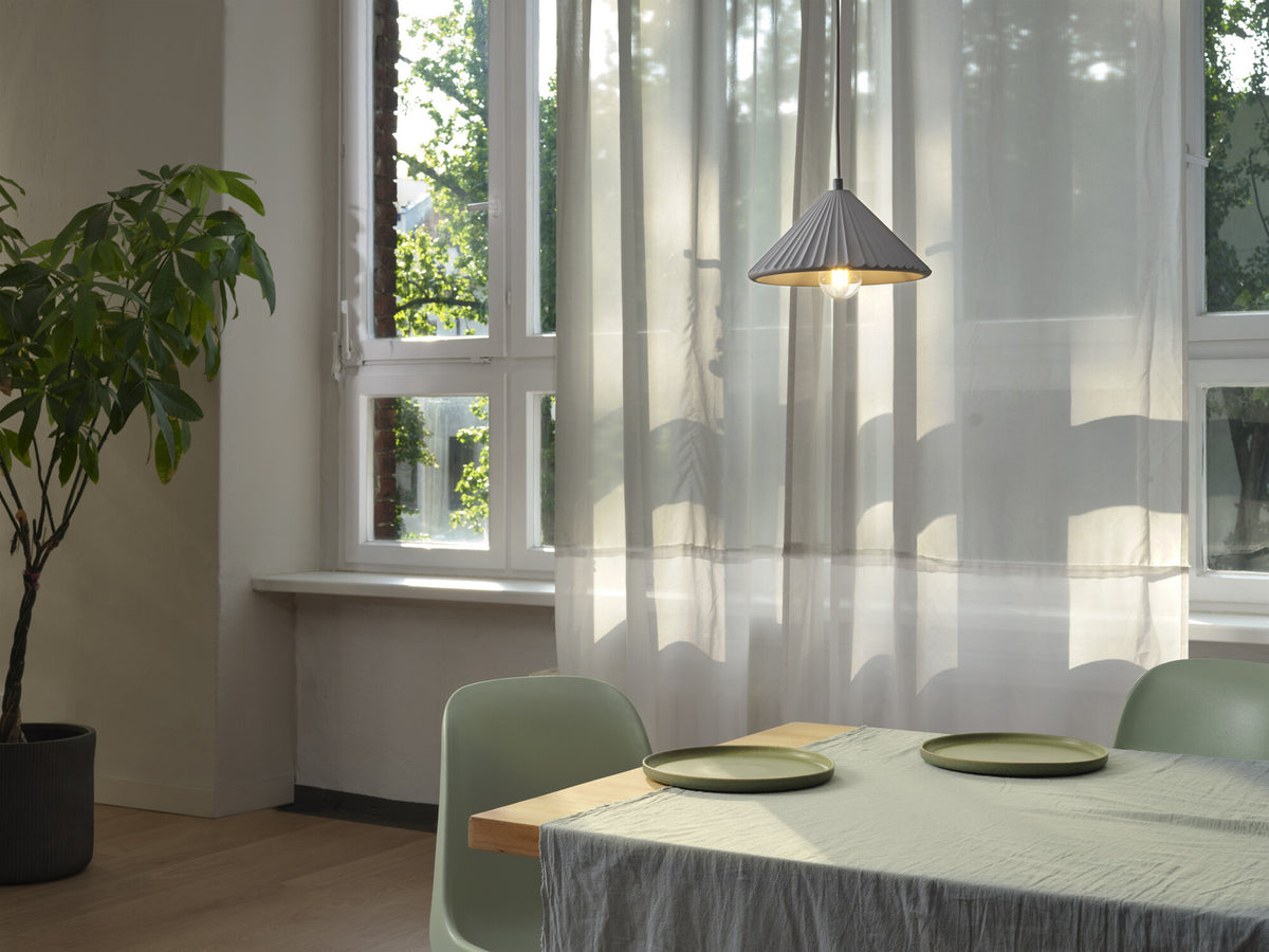 Mise en ambiance au-dessus d'une table dressée devant une fenêtre et des rideaux.