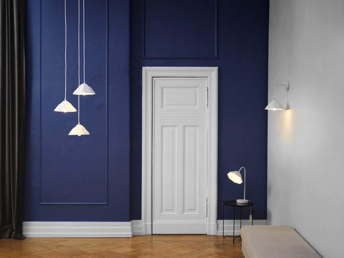 Mise en ambiance dans un couloir bleu, avec suspension et applique murales blanches.