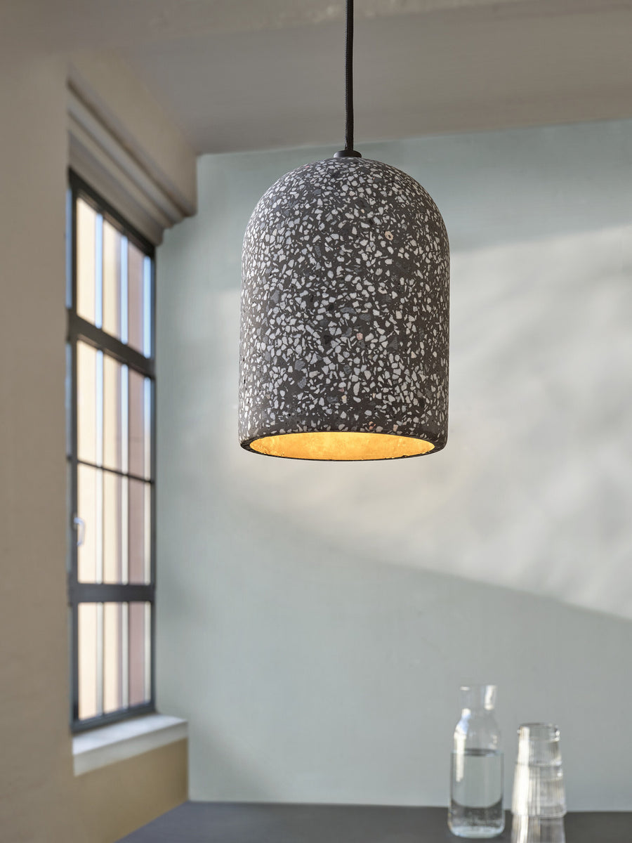 Gros plan sur l’abat-jour terrazzo noir et son intérieur doré éclairé.