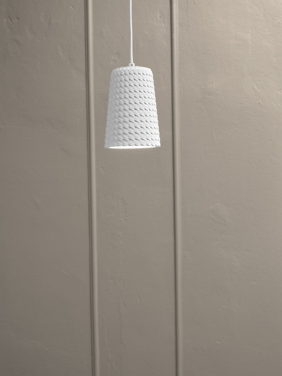 Détail de l'abat-jour conique en plâtre, texture tressée et lumière chaude.