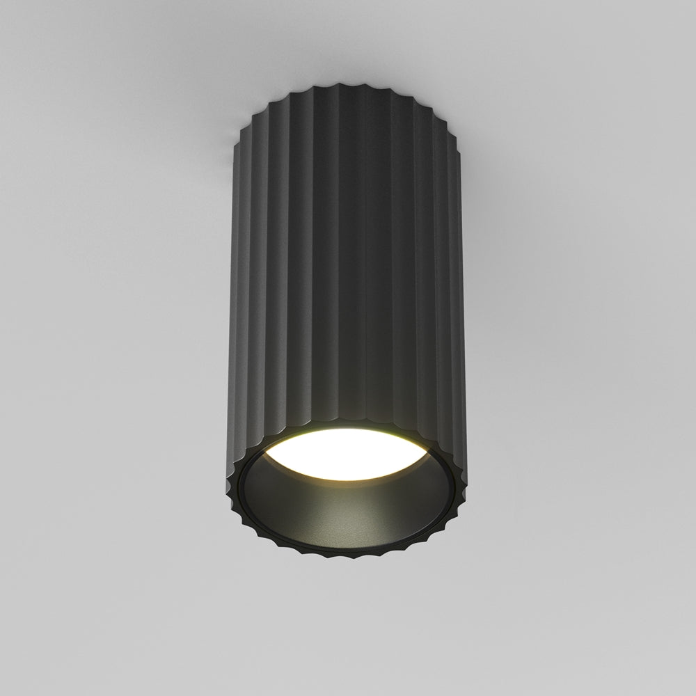 Plafonnier noir cylindrique cannelé fixé au plafond, éclairage allumé, vue de face