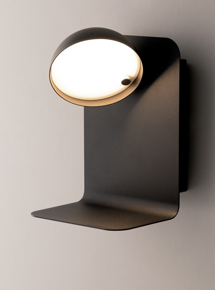 Vue de trois quarts du luminaire mural noir, tête ronde inclinée avec diffuseur blanc lumineux