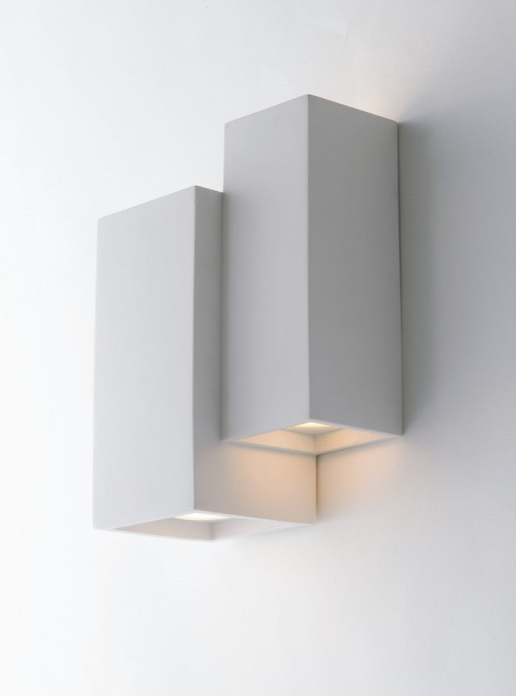 Vue rapprochée du luminaire mural blanc, volumes cubiques décalés et halo lumineux diffus