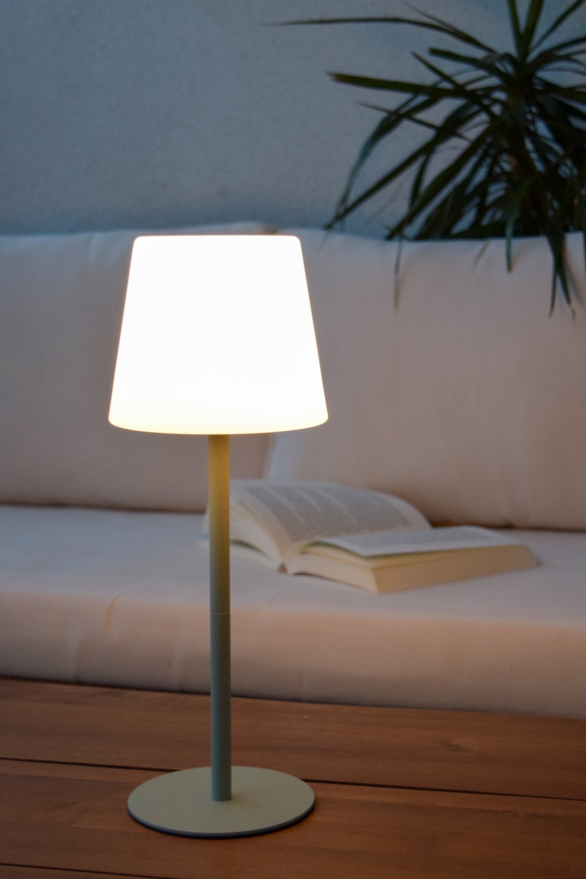 Mise en ambiance nocturne sur canapé blanc, lampe allumée près d'un livre ouvert