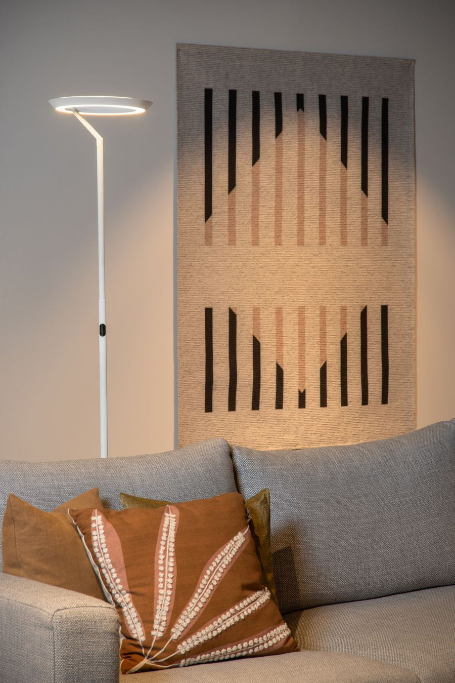 Vue de face du lampadaire blanc devant une tapisserie murale beige