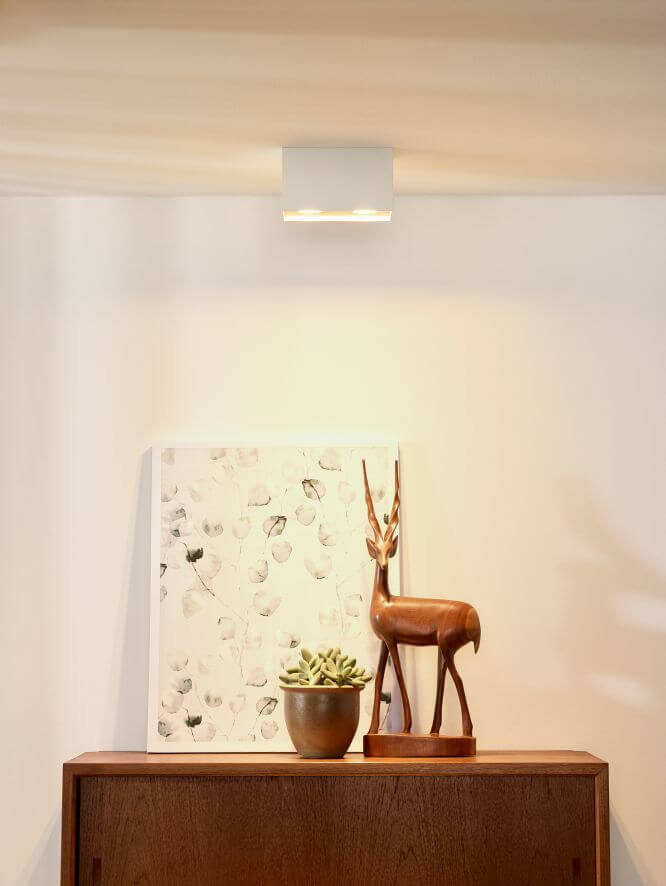 Plafonnier blanc rectangulaire allumé au plafond, au-dessus d'un buffet en bois décoré