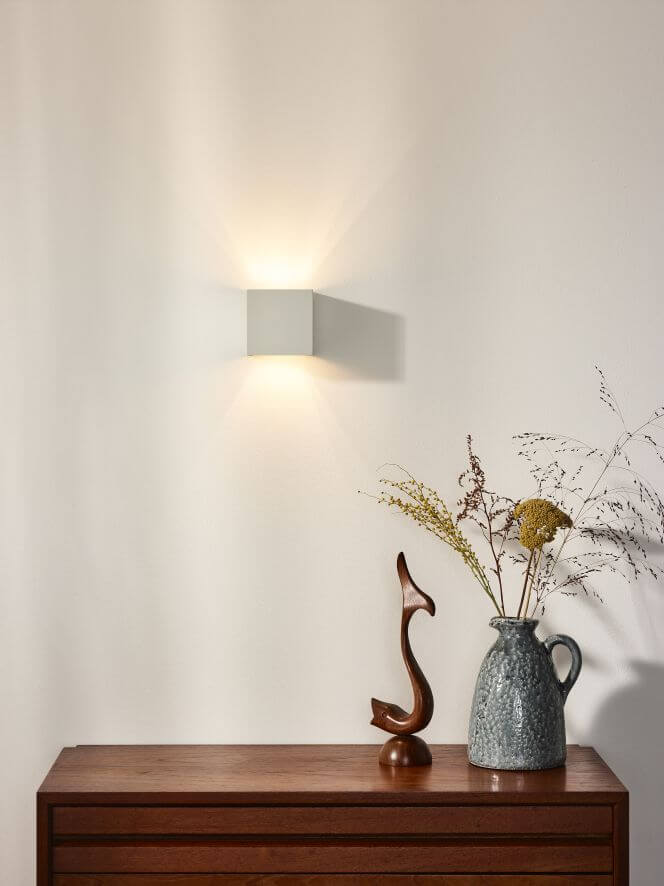 Mise en ambiance : lumière chaude diffusée en haut et en bas sur le mur blanc