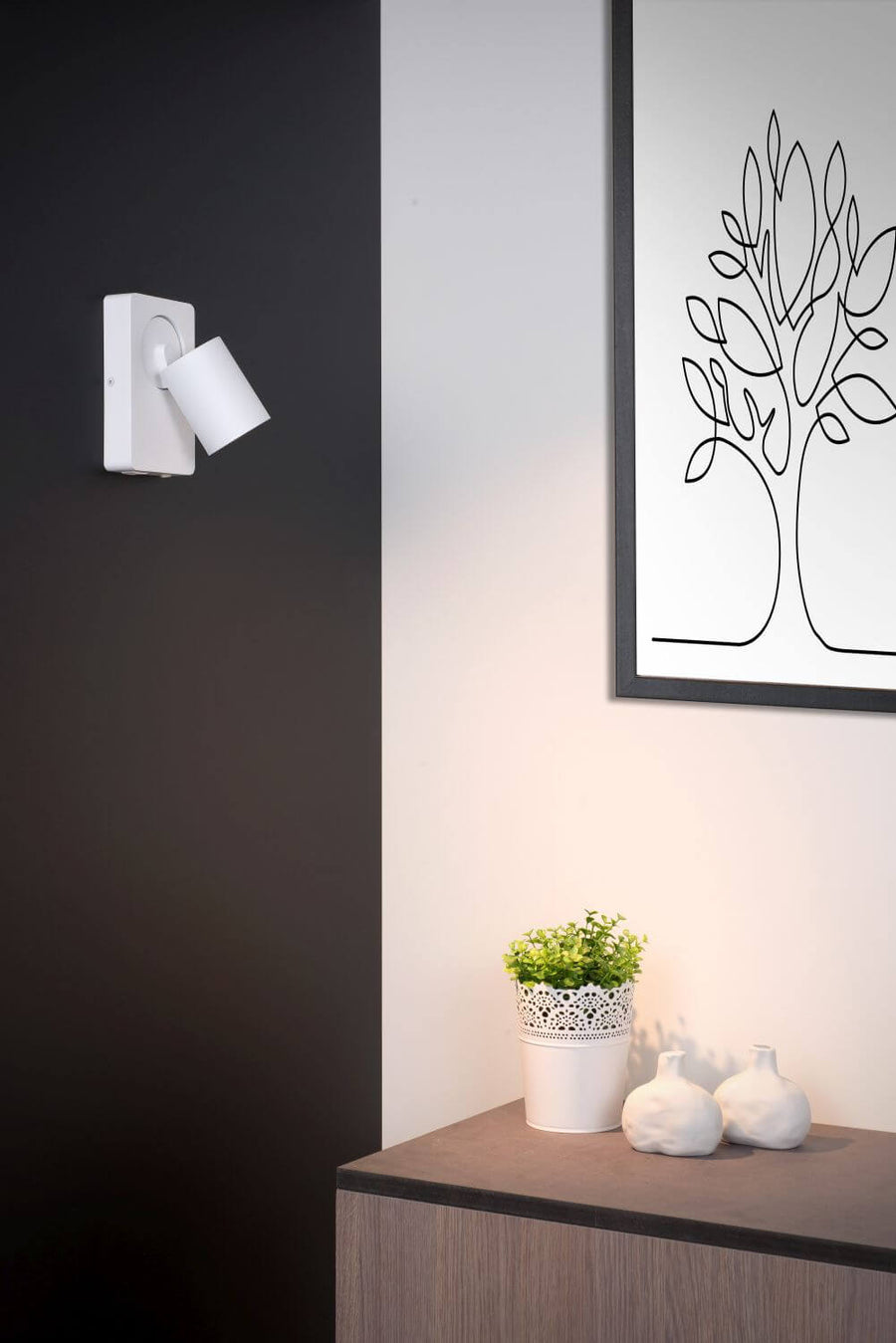 Vue rapprochée de l'applique blanche sur mur foncé avec cadre décoratif.