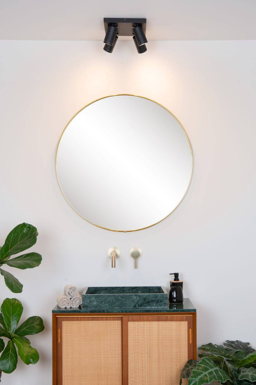 Plan rapproché du plafonnier noir et de ses quatre projecteurs orientables au-dessus du miroir doré.