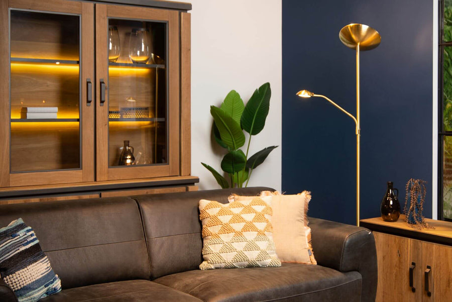 Lampadaire doré allumé dans un salon en cuir, près d'une vitrine en bois