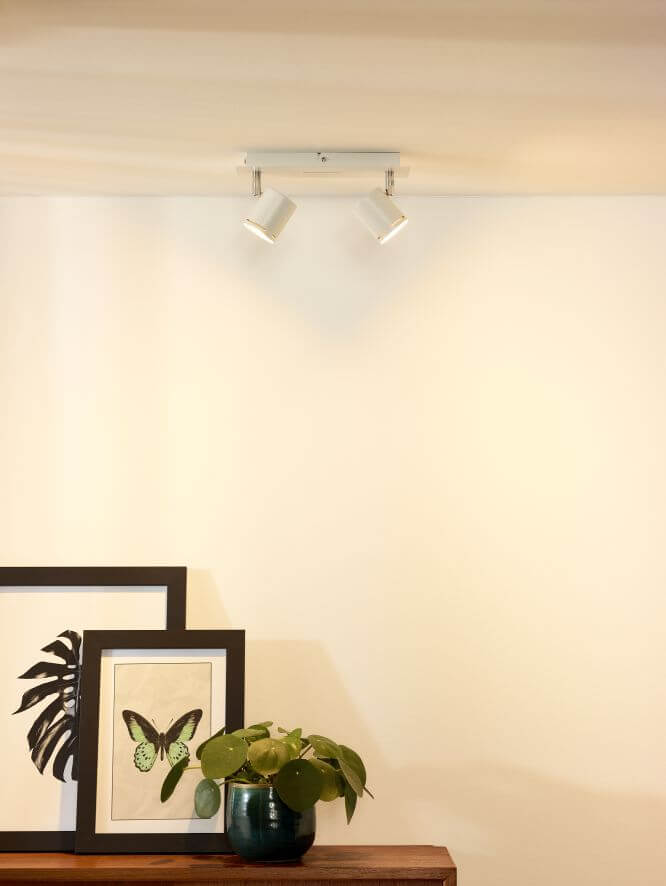 Plafonnier à deux spots orientables blanc et chrome installé au plafond dans une pièce.