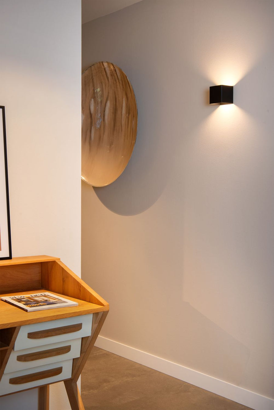 Mise en situation dans une entrée avec meuble en bois clair et miroir rond doré