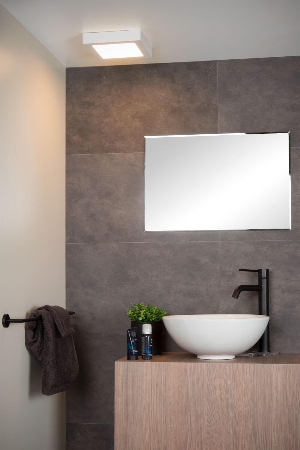 Vue rapprochée du plafonnier blanc carré éclairé, fixé au plafond au-dessus du miroir