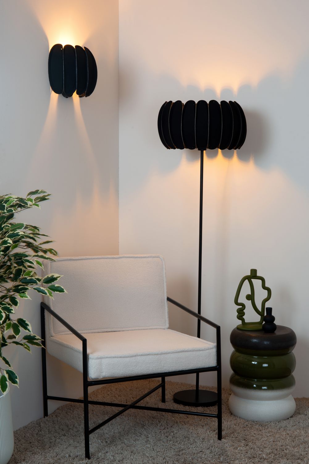 Plan rapproché du fauteuil blanc et de l'applique murale noire allumée sur le mur.
