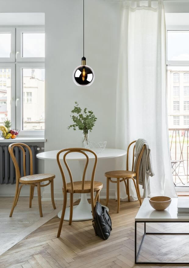Mise en ambiance dans une pièce à parquet chevrons, lampe suspendue au-dessus de la table