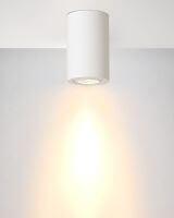 Lumière chaude projetée sur un mur par le plafonnier blanc allumé.