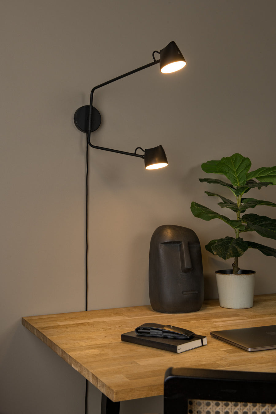 Vue rapprochée de l'applique allumée éclairant un bureau et une plante verte