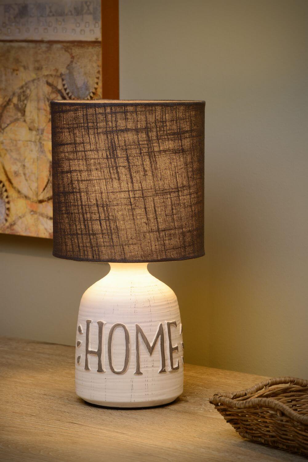 Gros plan de la lampe allumée, abat-jour en coton et lettrage HOME.