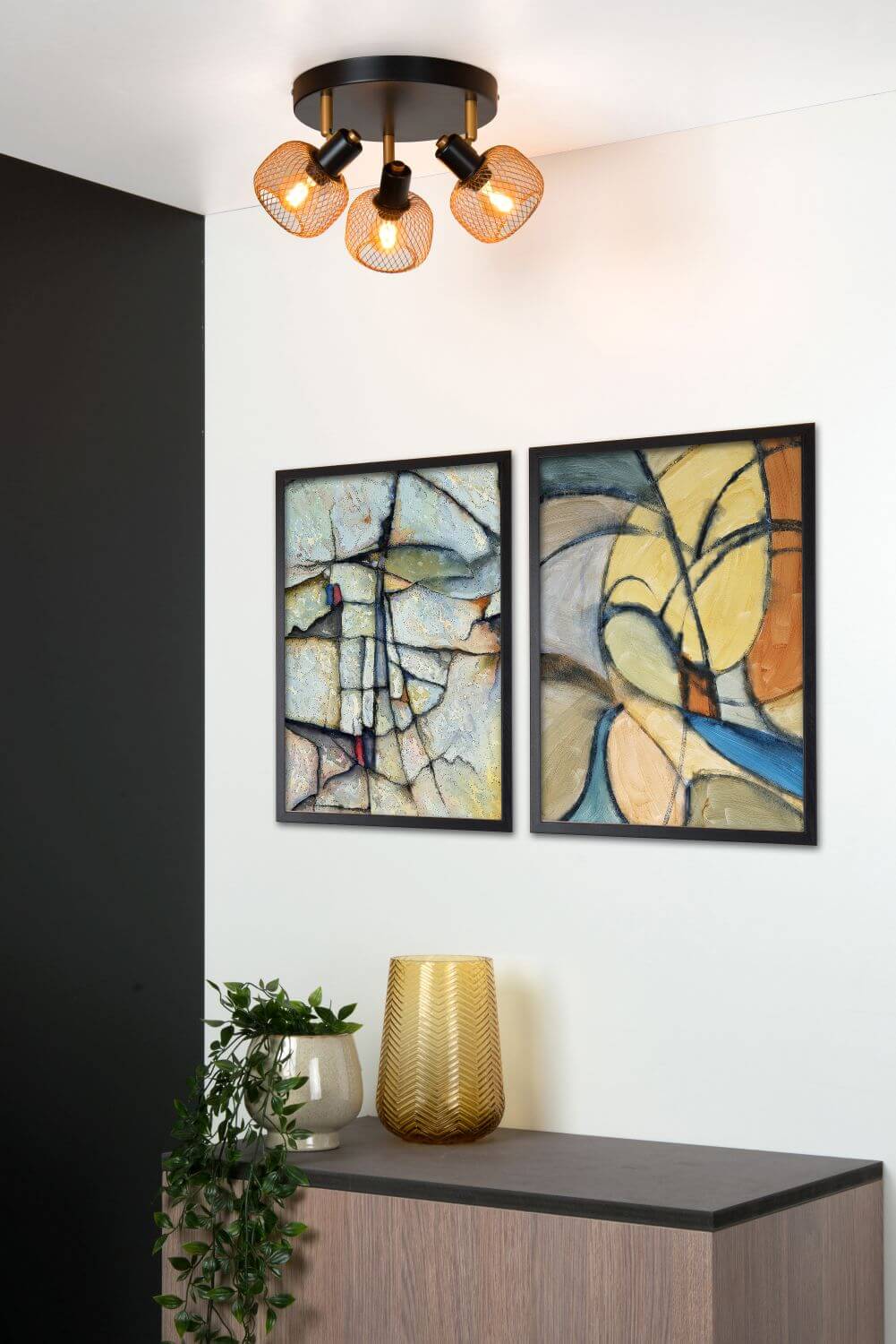 Vue en situation du luminaire trois lumières sous un plafond blanc avec tableaux