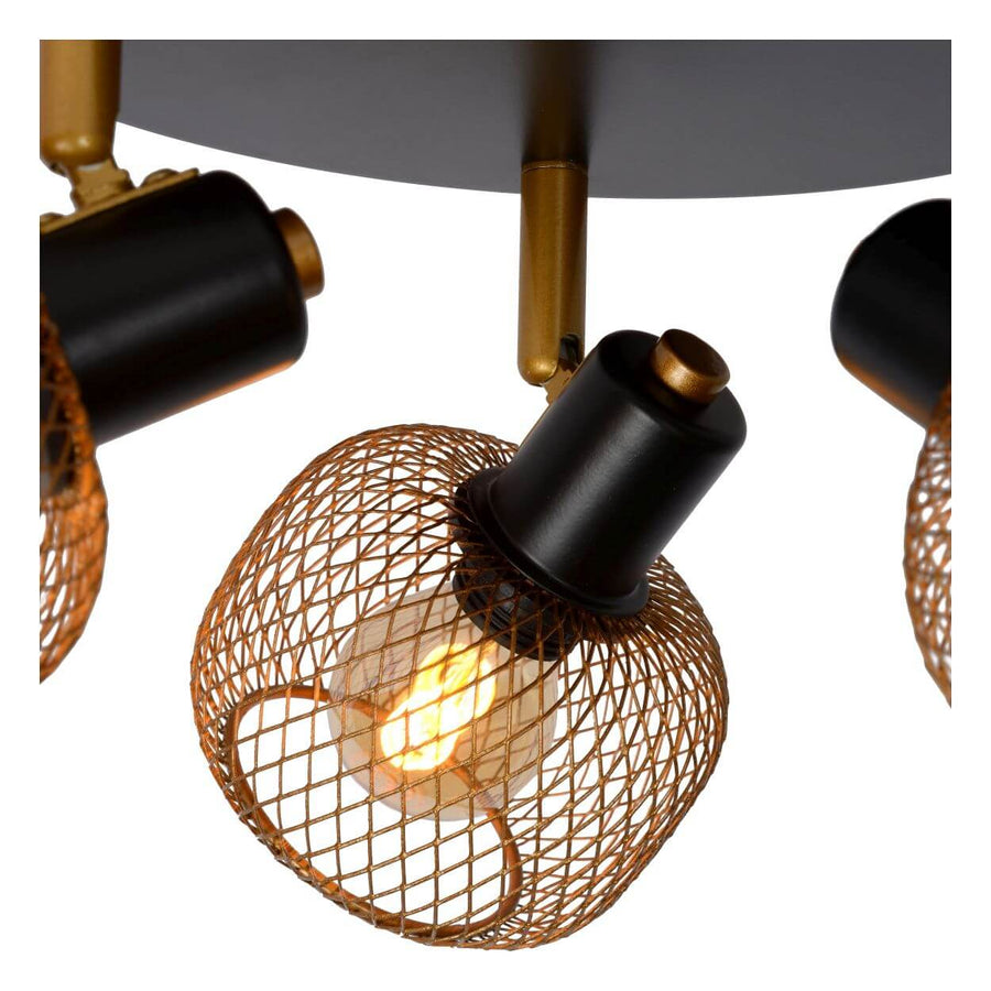 Détail rapproché d'une cage sphérique dorée et de l'ampoule allumée à l'intérieur