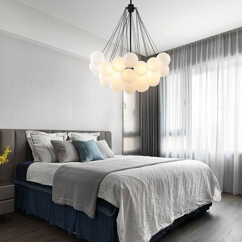 Lustre grappe de boules blanches suspendu au-dessus d'un lit dans une chambre claire