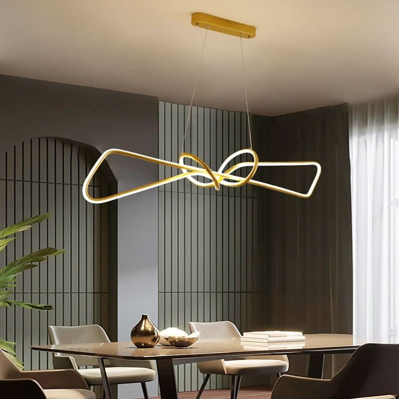 Lustre doré en boucle nouée suspendu au-dessus d'une table à manger en bois clair