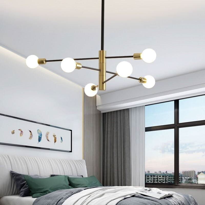 Lustre suspendu dans une chambre, six globes lumineux, bras noirs et finitions dorées visibles.