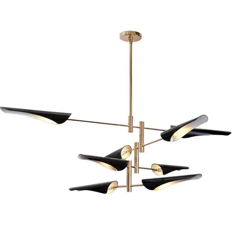 Détail du lustre noir et doré, bras croisés et abat-jours coniques orientables sur fond blanc.