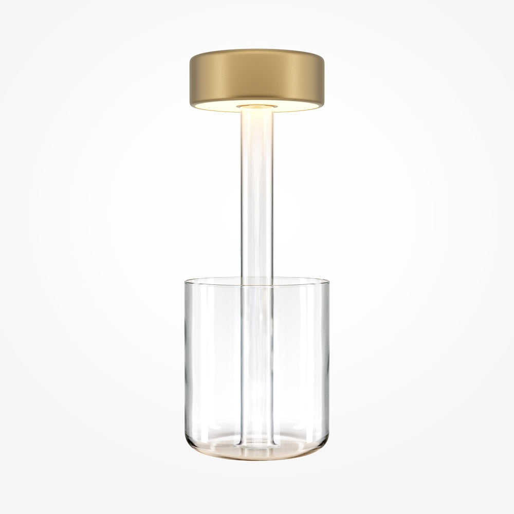 Lampe de chevet dorée sur tige transparente posée dans un vase en verre cylindrique