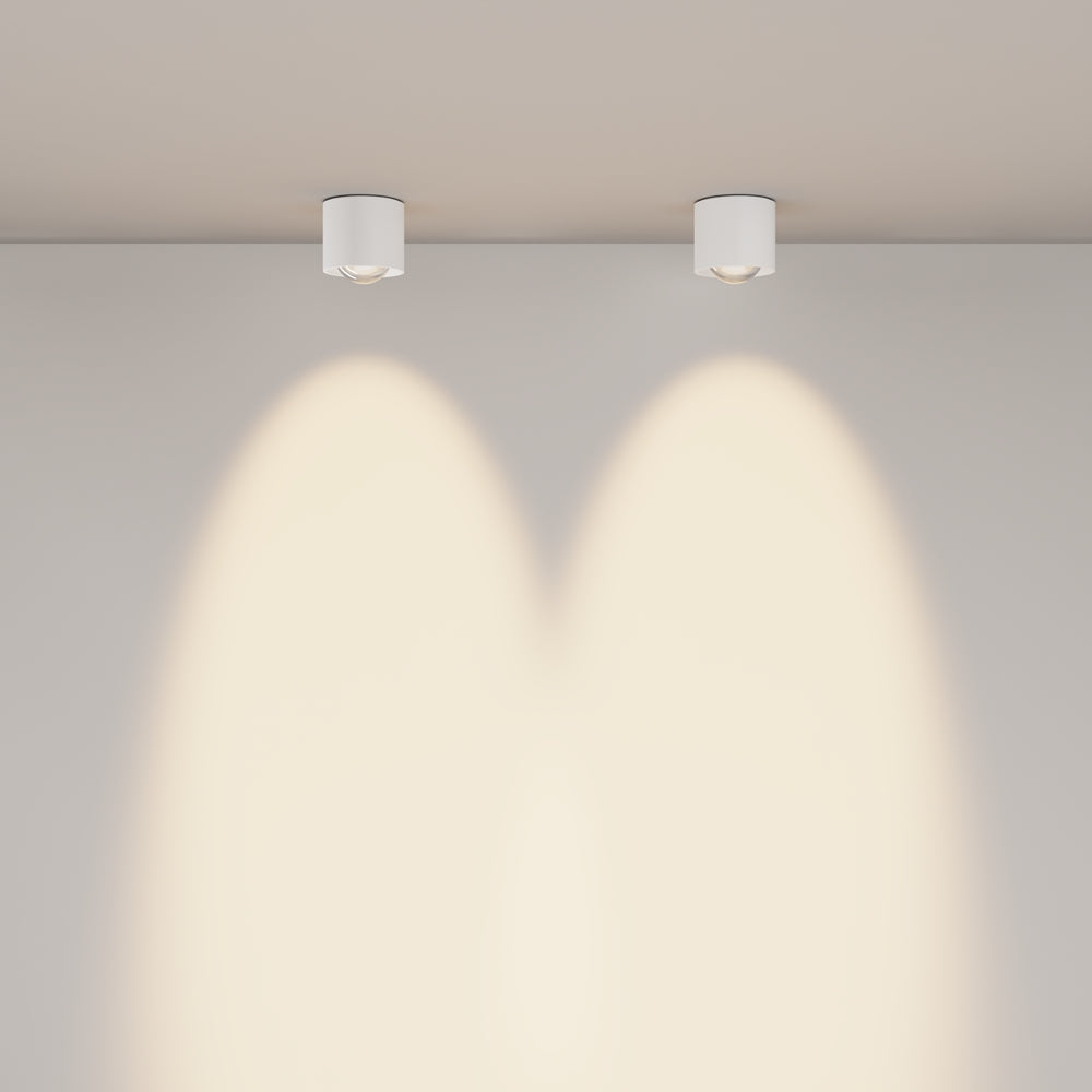 Deux plafonniers blancs installés au plafond projettent deux faisceaux sur le mur.