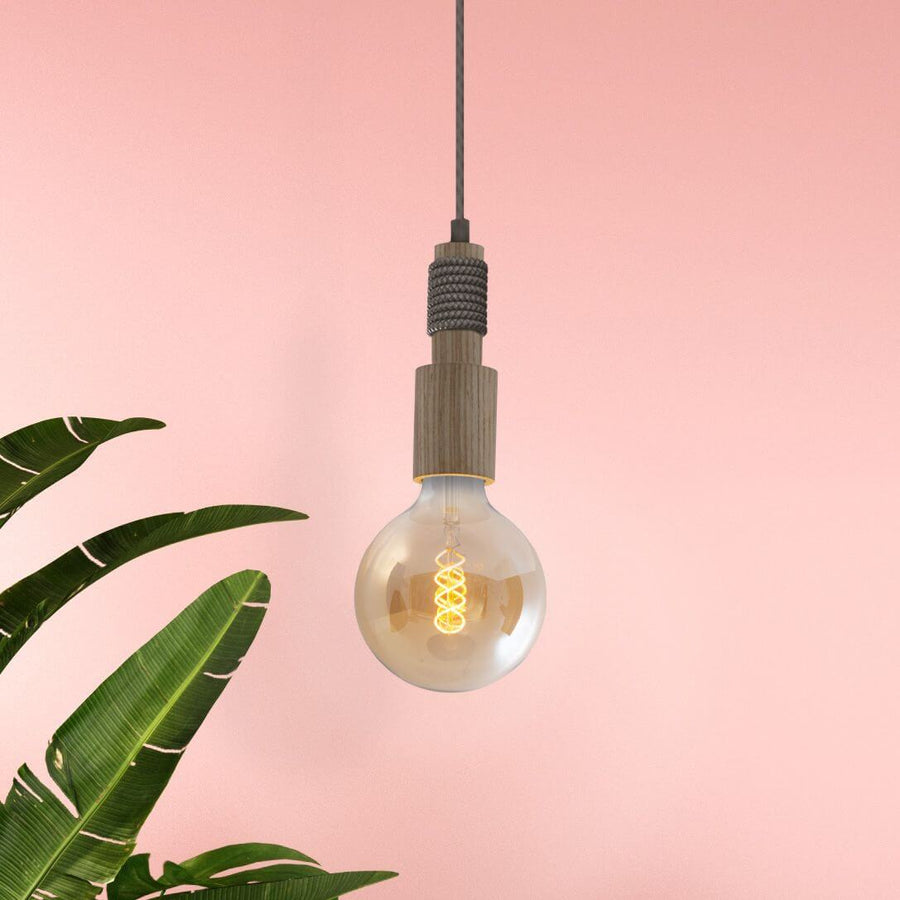 Gros plan sur la douille en bois et l'ampoule à filament, fond rose
