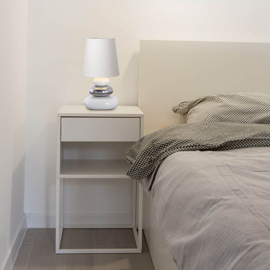 Lampe blanche posée sur une table de nuit blanche dans une chambre minimaliste