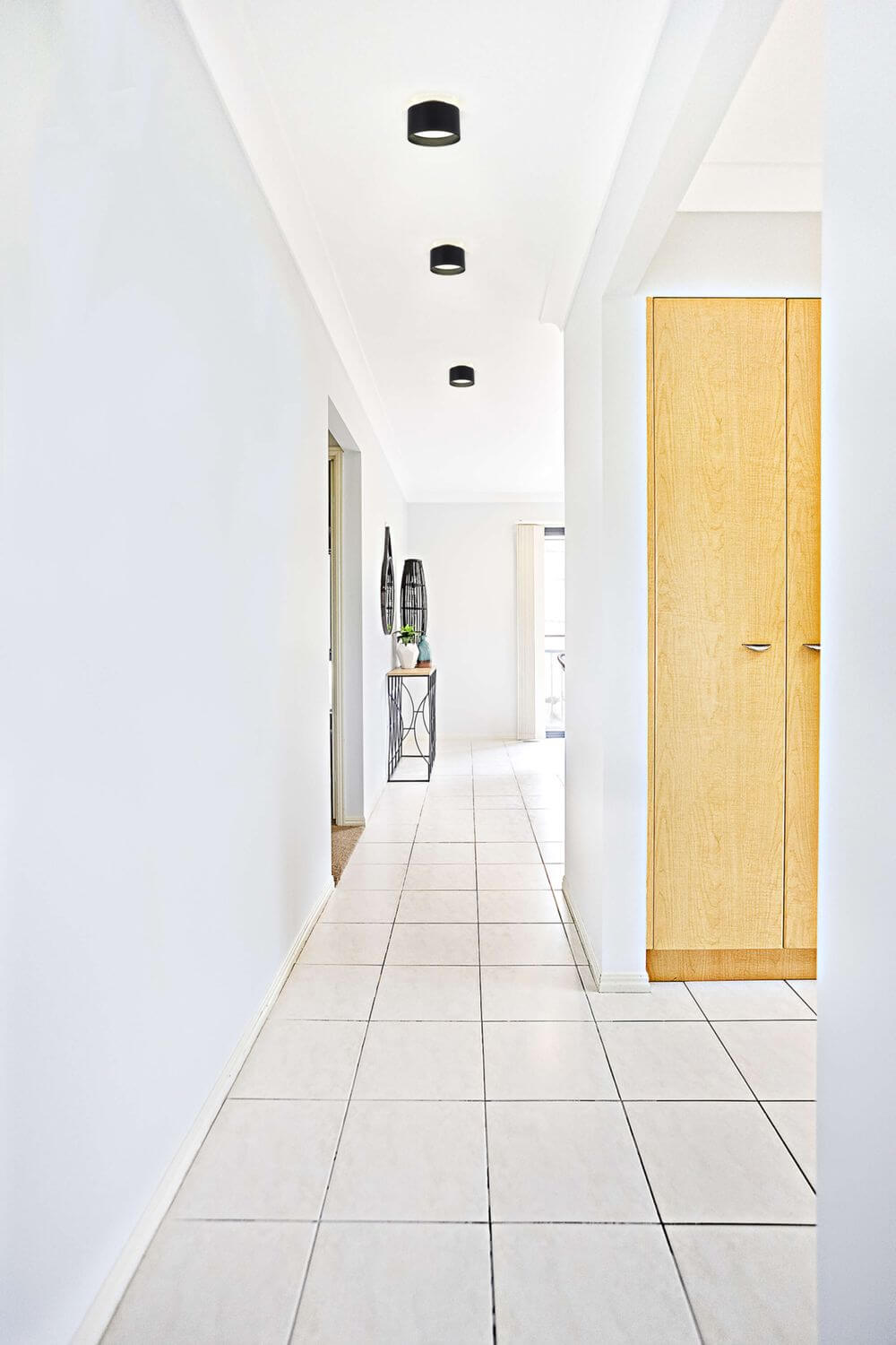 Mise en ambiance de trois plafonniers noirs alignes dans un couloir clair