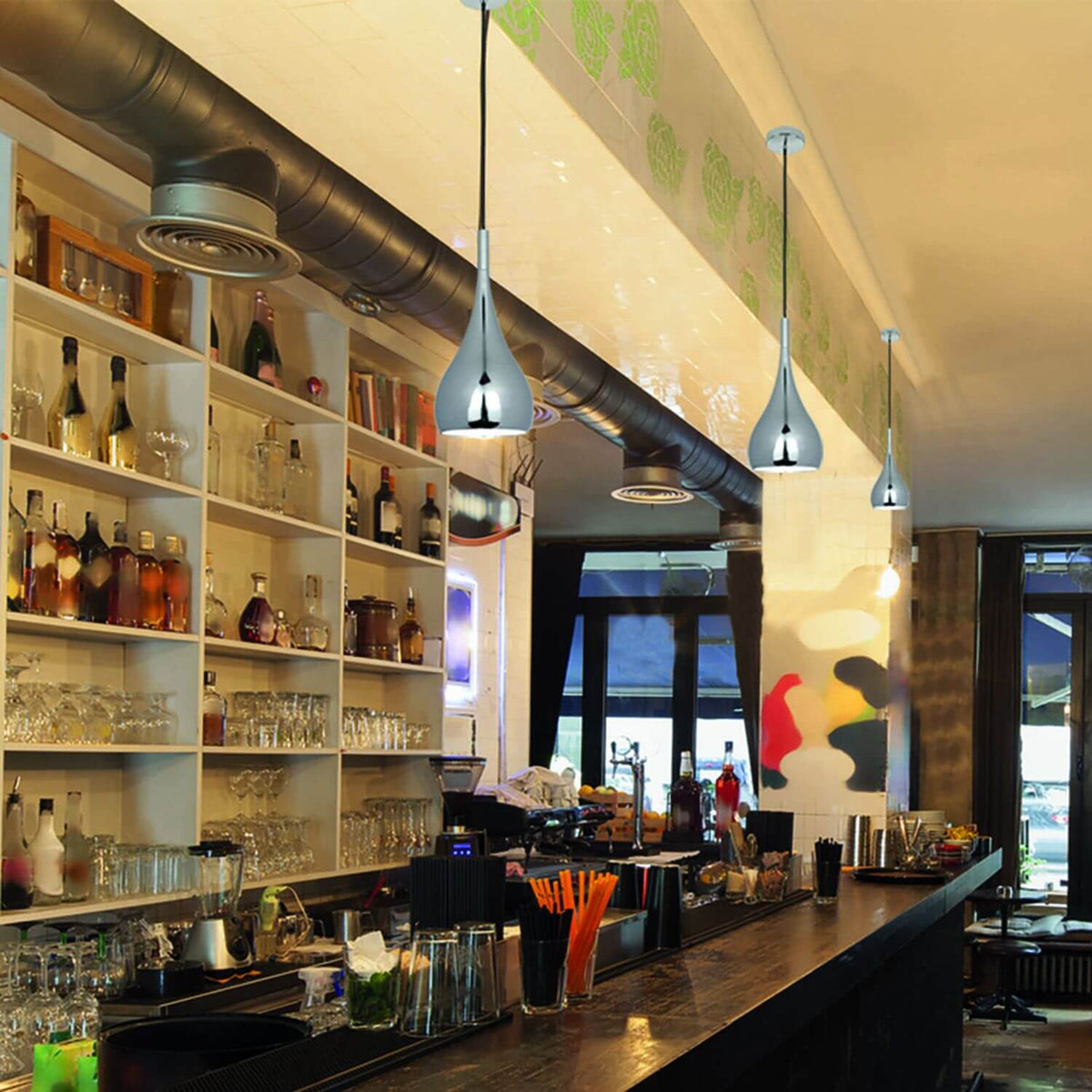 Vue rapprochée des suspensions en ambiance, mêlant reflets chromés et étagères de bar.