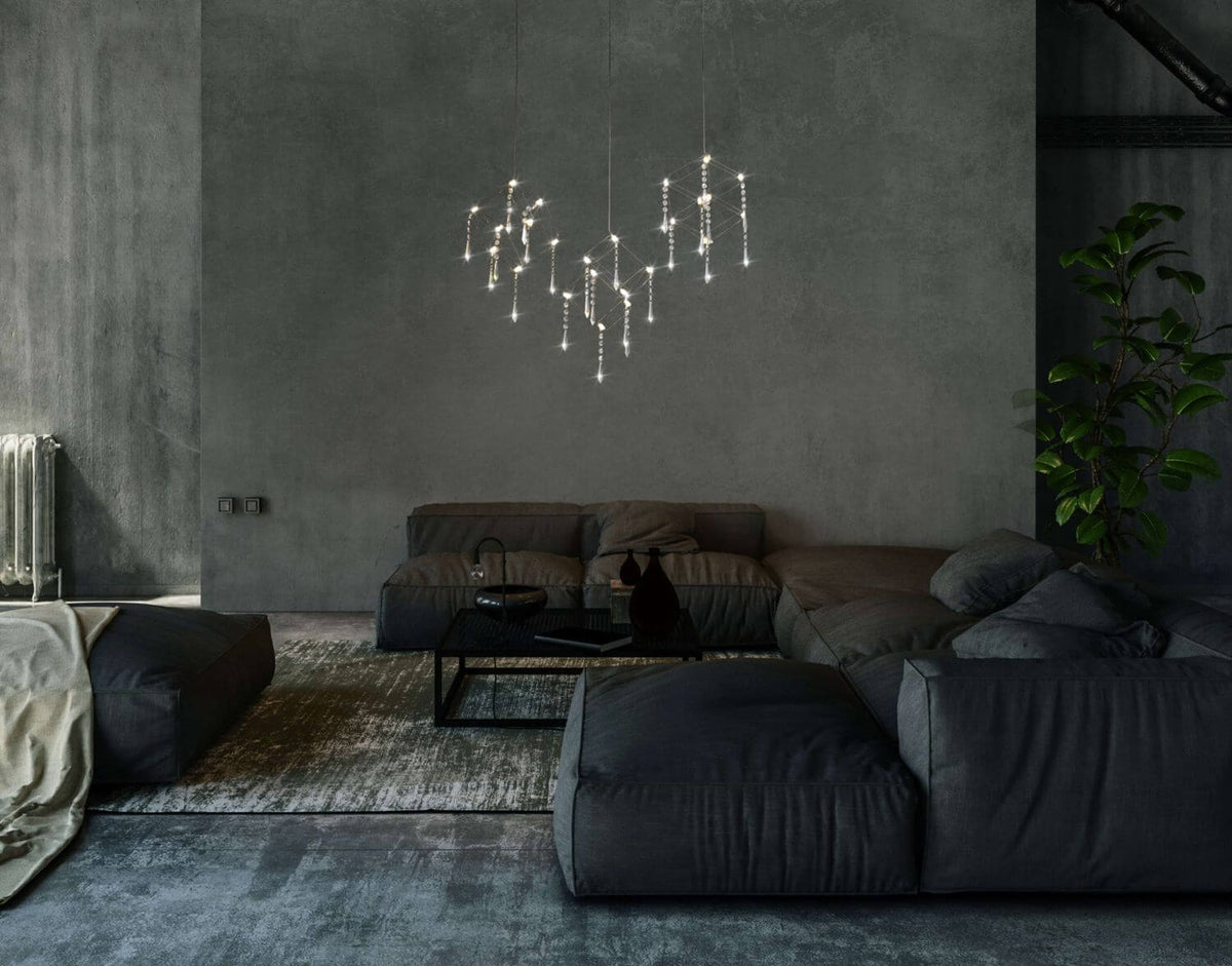 Vue rapprochée de la suspension allumée dans un salon contemporain aux canapés anthracite.
