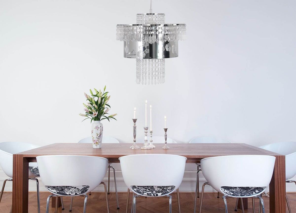 Mise en ambiance : suspension chromée au-dessus d'une table en bois avec chaises blanches.