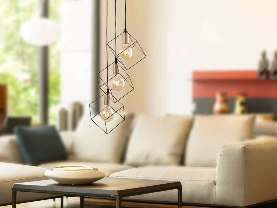 Luminaire suspendu au-dessus d'un coin salon, canapé beige et table basse en arrière-plan.
