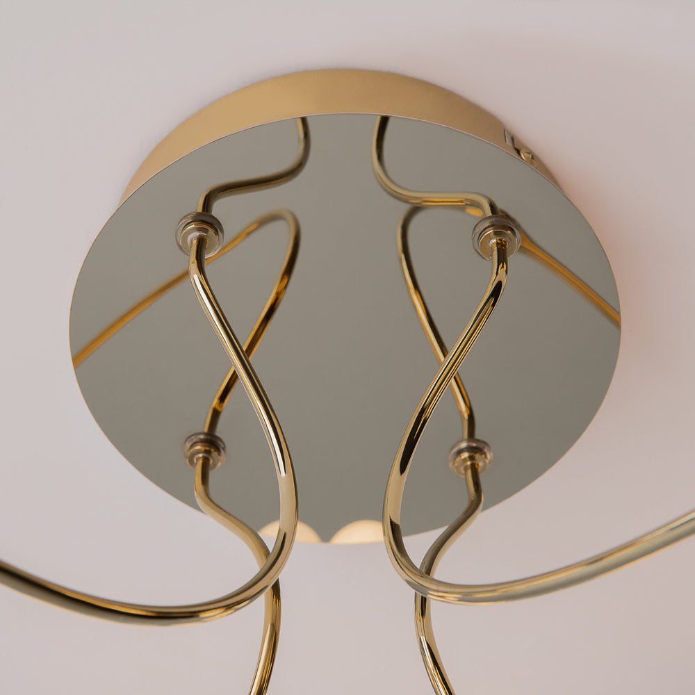 Détail du support central doré et réfléchissant avec ses bras recourbés.