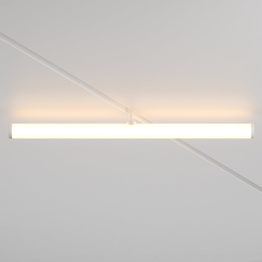 Luminaire tubulaire allumé de face, fixé sous un rail blanc au plafond