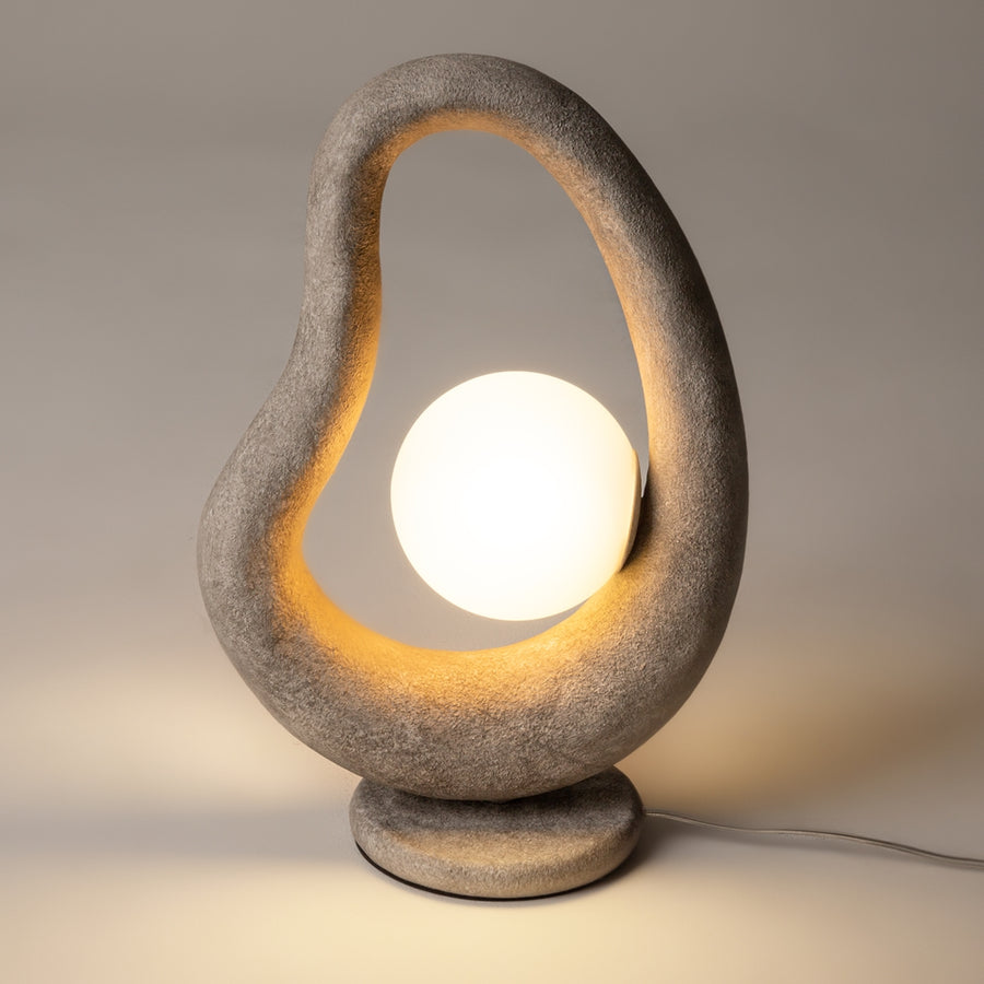 Vue de face du luminaire allumé, halo chaud soulignant l'intérieur de la boucle.