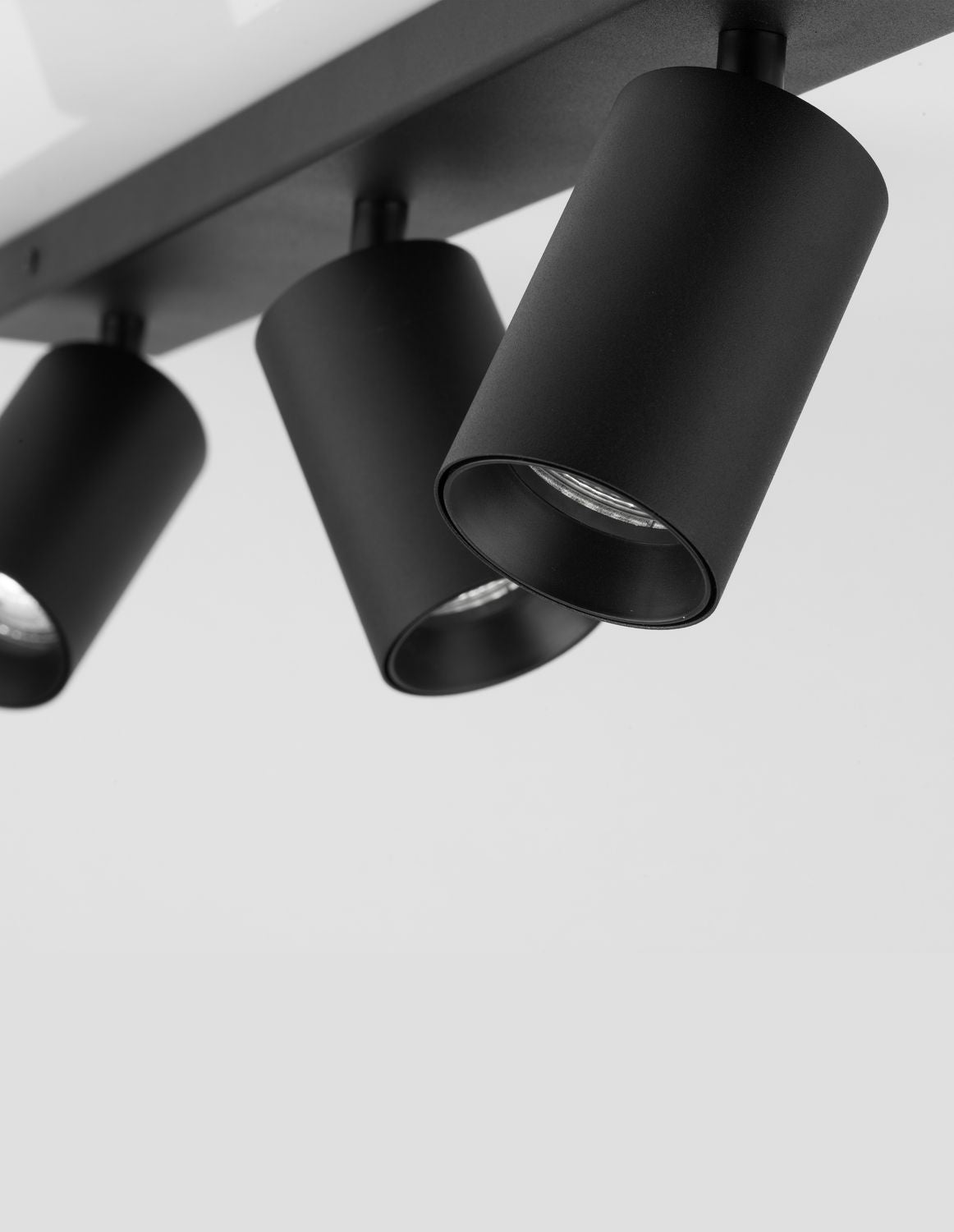 Gros plan en plongée sur trois spots cylindriques noirs orientables, finition mate