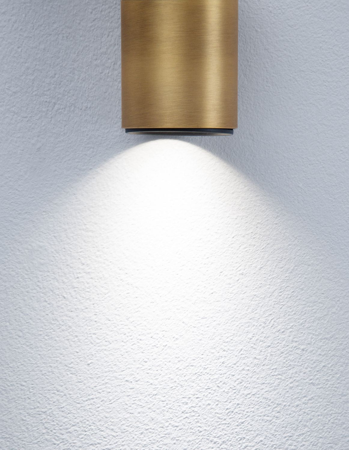 Détail du faisceau lumineux projeté sur un mur blanc par le spot doré