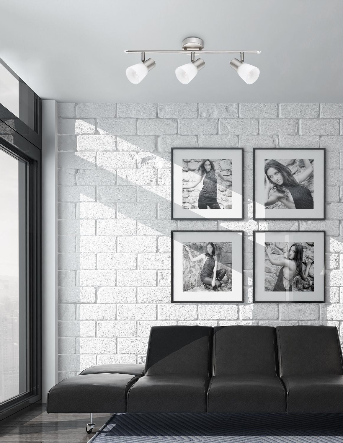 Luminaire plafonnier trois spots orientables monté au plafond dans un salon, au-dessus d'un canapé noir.