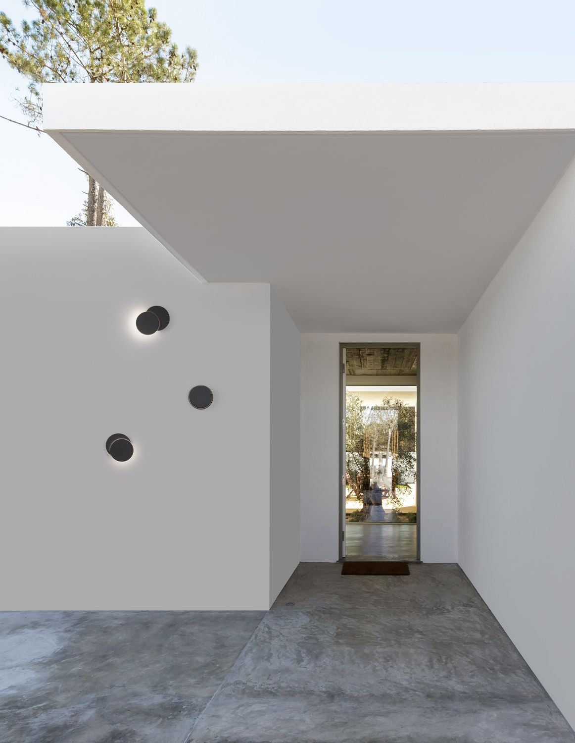 Applique murale noire installée sur un mur blanc extérieur sous un porche