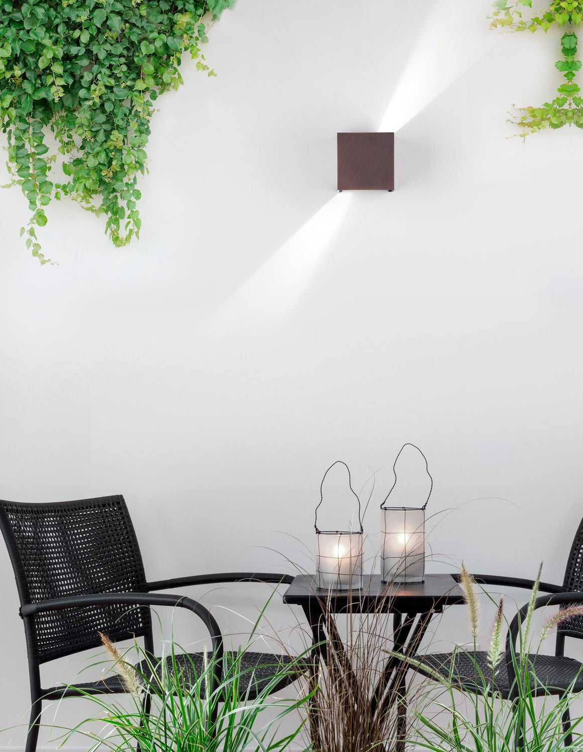 Photo d'ambiance : applique murale extérieure marron sur mur blanc, éclairage haut et bas.