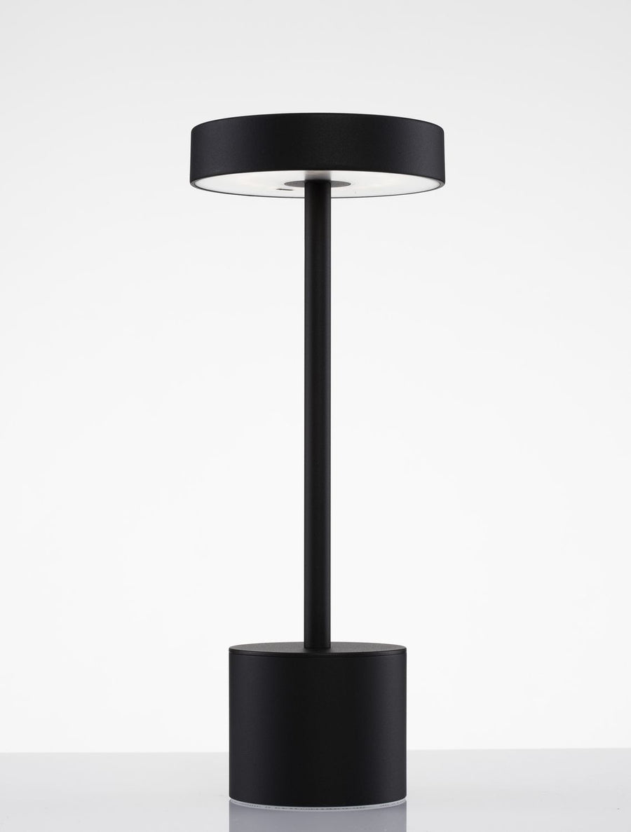Détail du luminaire noir, dessous de l'abat-jour circulaire éclairé sur fond blanc.