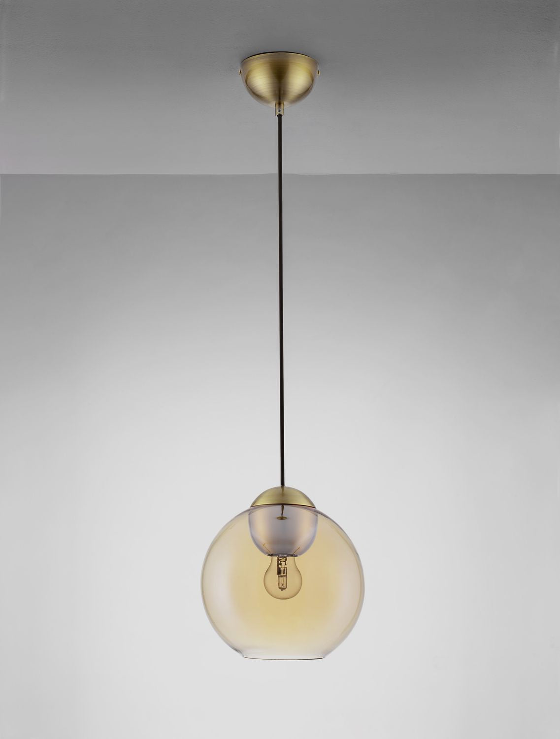 Suspension présentée en ambiance, câble tendu et diffuseur en verre ambré légèrement éclairé