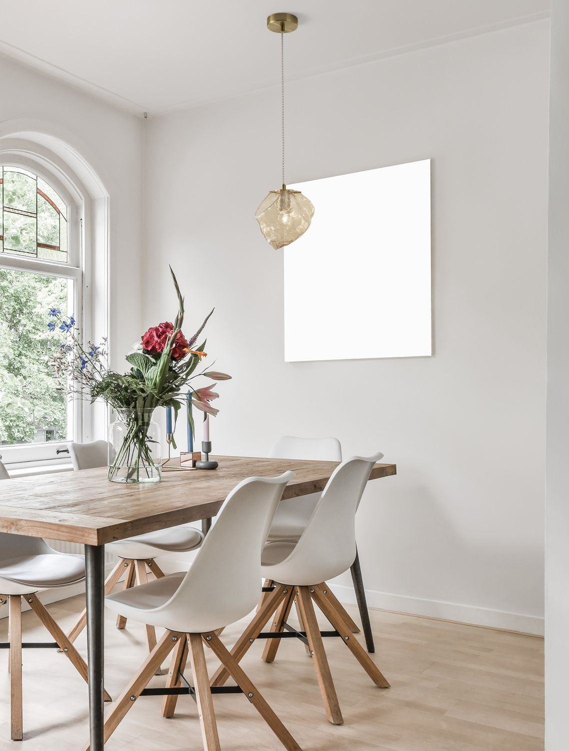Suspension dorée au-dessus d'une table en bois dans une salle à manger claire